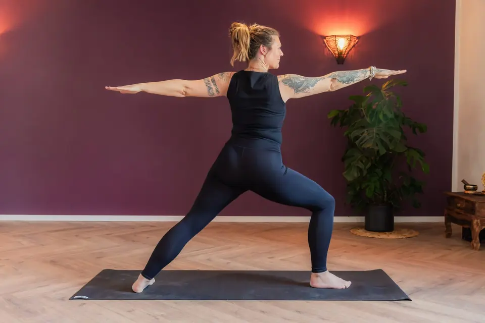 Frau in der Kriegerhaltung im Yogaraum